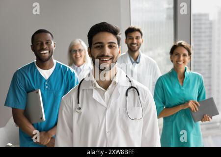 Medico che posa con un gruppo di diversi compagni di lavoro in ufficio Foto Stock