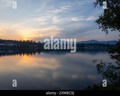 Un tramonto mozzafiato proietta sfumature dorate sul lago Placid, riflettendo la bellezza tranquilla delle montagne Adirondack sul lago Mirror, catturando il Foto Stock