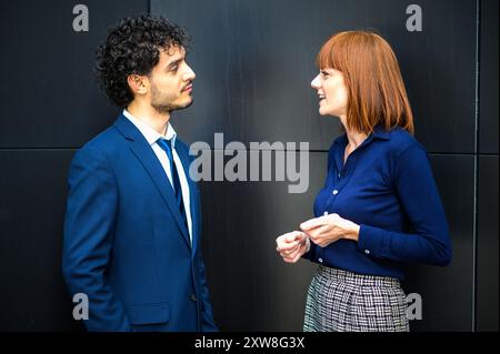 Due professionisti impegnati in una conversazione informale ma sincera in ufficio Foto Stock