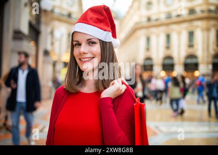 Una giovane donna sorridente vestita di rosso che fa shopping natalizio Foto Stock
