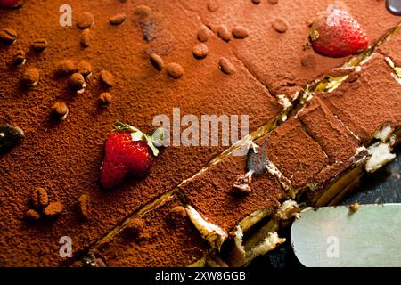 Primo piano di un tiramisù classico finemente spolverato con una corazza matura di fragole Foto Stock