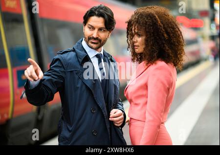 Due professionisti in abbigliamento formale si sono impegnati in una conversazione accanto a un treno Foto Stock