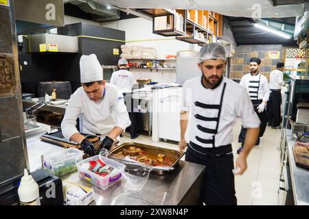 BAKU, AZERBAIGIAN-24 MAY2019 : lo chef prepara anche piatti con gambo di agnello. Il processo di cottura dello chef maschio dello stinco di agnello in una cucina professionale. Cucinare Foto Stock