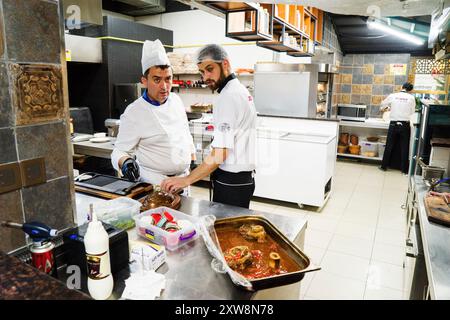 BAKU, AZERBAIGIAN-24 MAY2019 : lo chef prepara anche piatti con gambo di agnello. Il processo di cottura dello chef maschio dello stinco di agnello in una cucina professionale. Cucinare Foto Stock