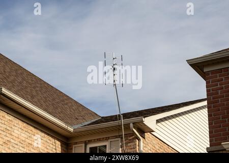 Sfondo blu chiaro con un'antenna Yagi multi-elemento montata sul tetto - casa residenziale in mattoni. Presa a Toronto, Canada. Foto Stock