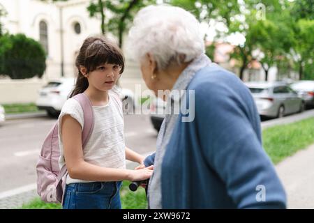 Nonna che spiega alla nipote come guidare uno scooter in sicurezza prima di partire per la scuola. Foto Stock