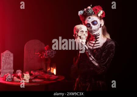 Inquietante signora che abbraccia il cranio alle processioni religiose durante la festa di novembre di dia de los Muertos. Donna che mostra rispetto per i membri della famiglia deceduti facendo un gesto amorevole verso il cranio Foto Stock