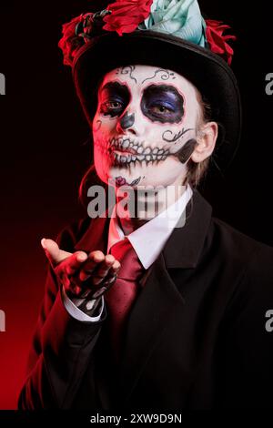 Lady che fa il viso bacio durante le processioni religiose durante la festa di novembre di dia de los Muertos. Donna che soffia bacio, indossa trucco scheletrico che simboleggia la riverenza per il defunto Foto Stock