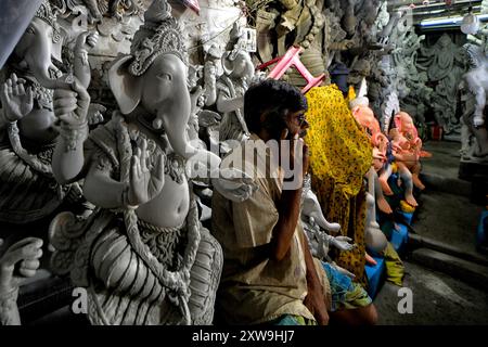 Kolkata, India. 17 agosto 2024. Un commerciante siede con gli idoli Ganesha nel suo negozio prima del festival Ganesh Chaturthi. Il festival Ganesh Chaturthi è il festival annuale di culto degli indù e si ritiene che il Signore Ganesha sia il dio dei nuovi inizi e la rimozione degli ostacoli, nonché il dio della saggezza, dell'intelligenza, della fortuna e della prosperità. Credito: SOPA Images Limited/Alamy Live News Foto Stock