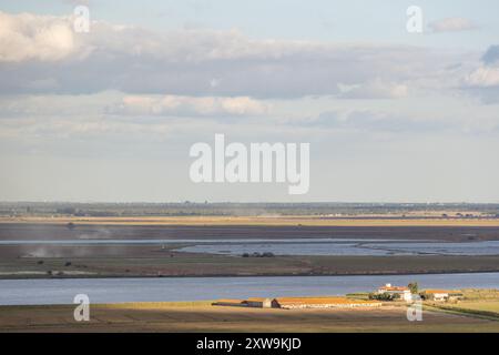 Vista panoramica del fiume tago che si snoda attraverso un vasto paesaggio, passando da una fattoria e da paludi salate sotto un cielo nuvoloso Foto Stock