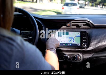 Donna in un'auto che imposta il gps prima di guidare. Utilizzo del sistema di posizionamento globale per la navigazione. Toccando con la mano lo schermo del monitor. Rosario, Argen Foto Stock