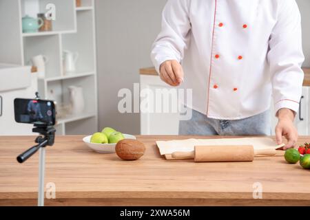 Chef maschio con impasto che registra video di cucina in cucina Foto Stock