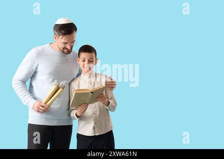 Felice padre ebreo e suo figlio piccolo con libri su sfondo blu Foto Stock