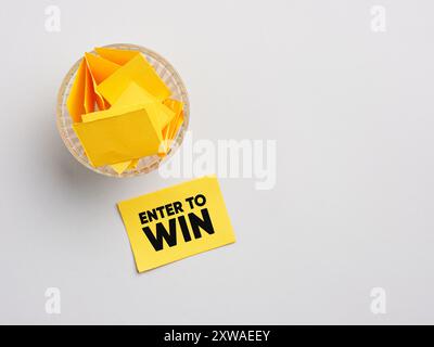Lotteria o estrazione a sorte. Per partecipare a un concorso o a una lotteria e vincere un premio. Biglietto della lotteria con la parola "ENTER" per vincere vicino a una ciotola di vetro piena di rotoli Foto Stock
