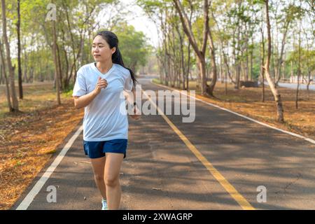 Giovane donna che corre da sola la mattina al parco di corsa locale in estate Foto Stock