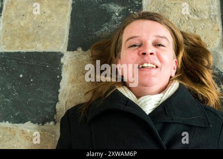 Ritrattista Breda, Paesi Bassi. Donna caucasica media adulta sdraiata su un pavimento mediavale della chiesa mentre sorride con gioia. Breda Down Town Noord-Brabant Nederland Copyright: XGuidoxKoppesxPhotox Foto Stock