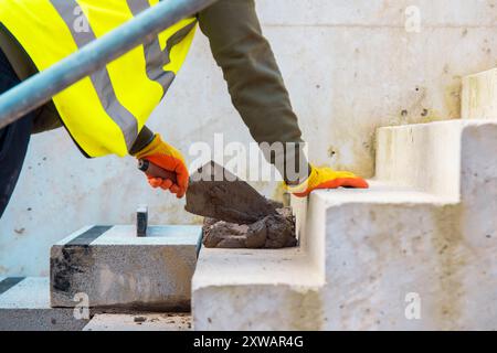 Passi concreti in costruzione come un team di costruttori installare blocchi di cemento pesanti Foto Stock