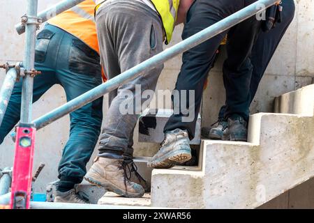 Passi concreti in costruzione come un team di costruttori installare blocchi di cemento pesanti Foto Stock