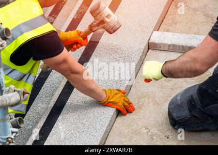 Passi concreti in costruzione come un team di costruttori installare blocchi di cemento pesanti Foto Stock