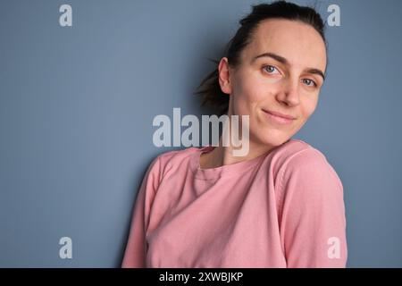 Foto ravvicinata di una donna elegante, moderna, affascinante e sorridente su sfondo blu Foto Stock