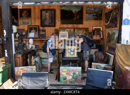 Saint-Ouen-sur-Seine (zona di Parigi): Mercato delle pulci di Saint-Ouen “marche aux puces”. Due uomini che guardano dipinti e opere d'arte in un negozio del Vernaison Foto Stock