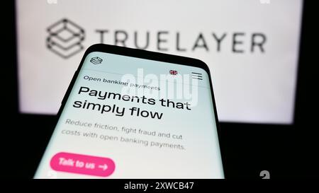Telefono cellulare con pagina web della società britannica di pagamenti bancari TrueLayer davanti al logo aziendale. Mettere a fuoco in alto a sinistra sul display del telefono. Foto Stock