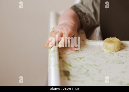 Mangia la mano del bambino sulla sedia a sdraio per esplorare il cibo Foto Stock