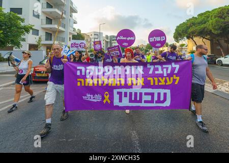 Haifa, Israele - 17 agosto 2024: Le persone partecipano a una marcia di protesta (gruppo in piedi), con vari segni e bandiere, contro il governo, Foto Stock