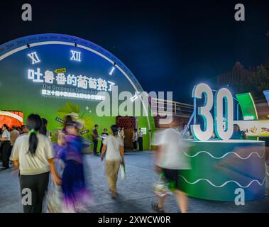 Turpan, la regione autonoma cinese dello Xinjiang Uygur. 16 agosto 2024. La gente cammina fino al luogo della cerimonia di apertura del 30° China Silk Road Turpan Grape Festival a Turpan, nella regione autonoma di Xinjiang Uygur, nel nord-ovest della Cina, 16 agosto 2024. Il festival dell'uva Turpan di tre giorni è iniziato venerdì. Con il suo clima secco e soleggiato, Turpan ha una lunga storia di coltivazione dell'uva ed è una delle principali basi di produzione dell'uva in Cina. La sua superficie di impianto ammonta a 42.000 ettari con 550 varietà di uve. Crediti: Chen Shuo/Xinhua/Alamy Live News Foto Stock