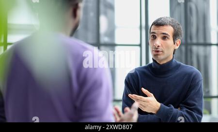 Diversi colleghi maschi amichevoli che parlano mentre camminano Foto Stock