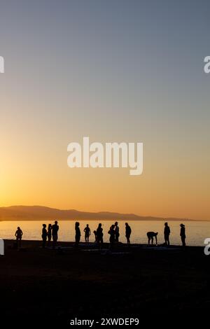 Gruppo di persone che si riuniscono per una sessione di yoga all'alba a Marbella, Spagna Foto Stock