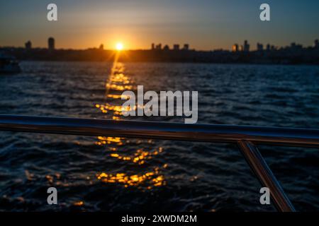 Uno splendido tramonto sul Bosforo di Istanbul, con il cielo che si illumina in calde tonalità di arancione e rosa, che proiettano una splendida luce sull'acqua e sulla città Foto Stock