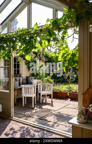 Vista dalla serra esposta a sud fino alla terrazza con giardino della casa di Wimbledon, a sud-ovest di Londra, Inghilterra, Regno Unito. Foto Stock