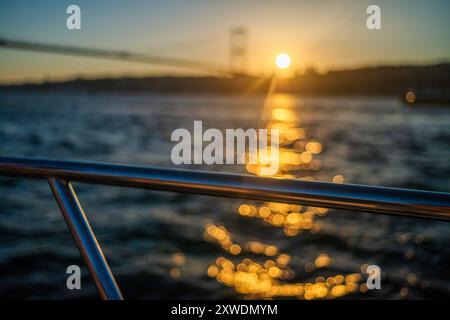 Le sfumature dorate del sole tramontare proiettano un caldo bagliore sul ponte e sulle acque tranquille, catturando l'eleganza della scena. Foto Stock