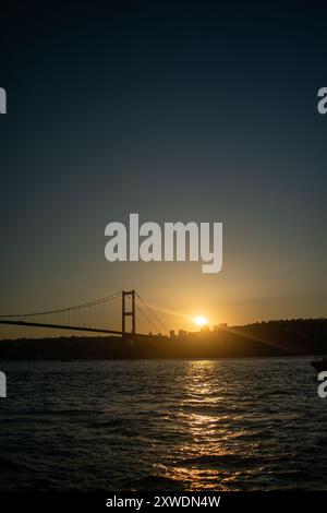 Le sfumature dorate del sole tramontare proiettano un caldo bagliore sul ponte e sulle acque tranquille, catturando l'eleganza della scena. Foto Stock