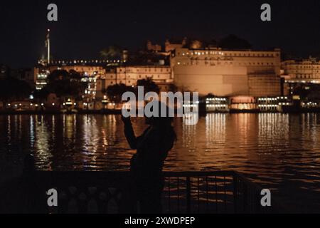 Una donna che fa clic su una foto sul suo telefono che si affaccia su un lago Foto Stock