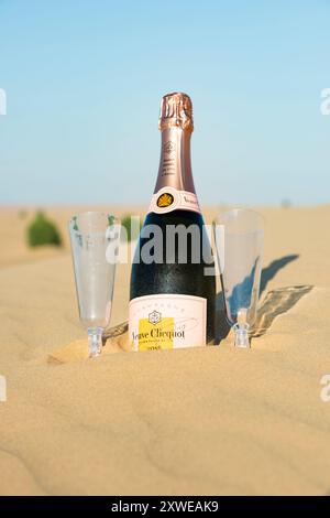 Bottiglia di champagne e due bicchieri vuoti sulla duna di sabbia, preparati per un aperitivo al tramonto sulle dune Foto Stock