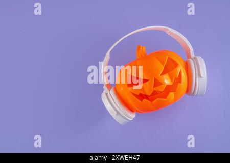 Musica di Halloween, playlist per il concetto di festa di Halloween. Pumpkin Jack Lantern in grandi cuffie bianche, su sfondo luminoso, copia spa Foto Stock