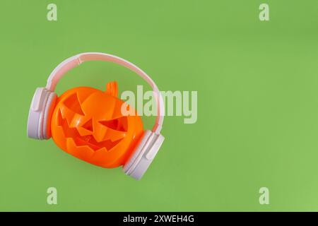 Musica di Halloween, playlist per il concetto di festa di Halloween. Pumpkin Jack Lantern in grandi cuffie bianche, su sfondo luminoso, copia spa Foto Stock