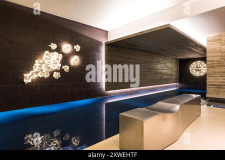 Piscina con illuminazione astratta e posti a sedere a bordo piscina in una lussuosa e moderna casa britannica. Londra, Regno Unito Foto Stock