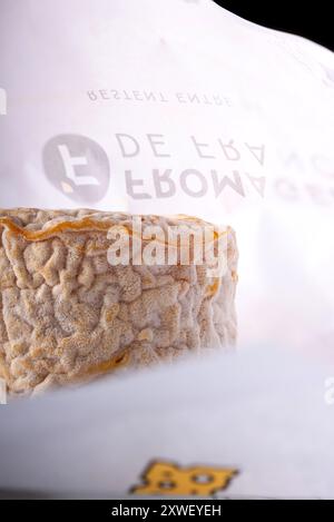 Formaggio Langres con carta da imballaggio originale sullo sfondo. Foto Stock