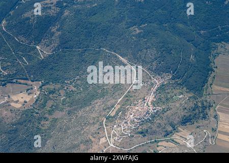 Panorama aereo panoramico della città, da un aereo da aliante, con il villaggio collinare di Castelvecchio Calvisio, girato da sud-est con la luce brillante dell'estate, Appennini, Foto Stock