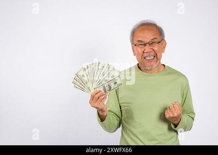 Ritratto vecchio asiatico sorridente sta tenendo in mano un mucchio di banconote in studio girato isolato su bianco Foto Stock