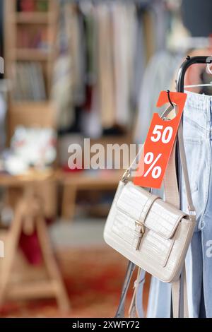 Borsa verticale in pelle bianca con cartellino di prezzo rosso appeso al portabiti in vendita con il 50% di sconto presso il negozio di seconda mano, spazio fotocopie Foto Stock