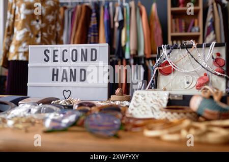 Primo piano sul cartello con la scritta "seconda mano" e la valigetta per gioielli con accessori vintage al check-out del negozio Thrift, spazio per le copie Foto Stock