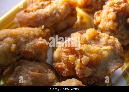 Primo piano di pezzi di pollo fritti dorati e croccanti, che mostrano la consistenza dettagliata dell'impasto croccante, perfetto per il contenuto alimentare. Foto Stock