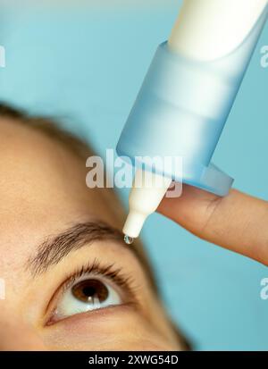 la ragazza utilizza gocce per idratare gli occhi, occhi stanchi dopo il lavoro, occhi secchi Foto Stock