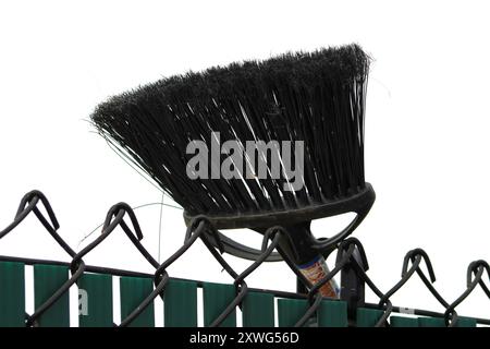 avvicinare la scopa nera appoggiata contro la recinzione delle maglie della catena Foto Stock
