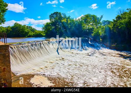 Vibrante cascata sulla diga artificiale nella lussureggiante area boschiva prospettiva a livello degli occhi Foto Stock