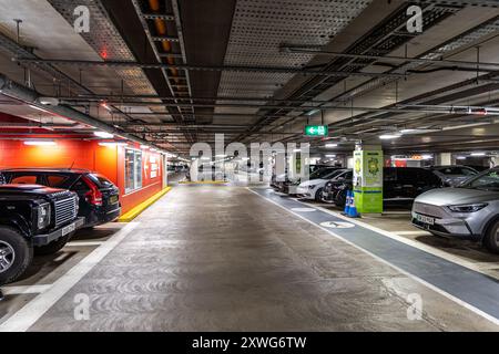 Oxford, Regno Unito - 5 giugno 2024: Parcheggio sotterraneo pieno di auto con postazioni di ricarica per auto elettriche. Foto Stock